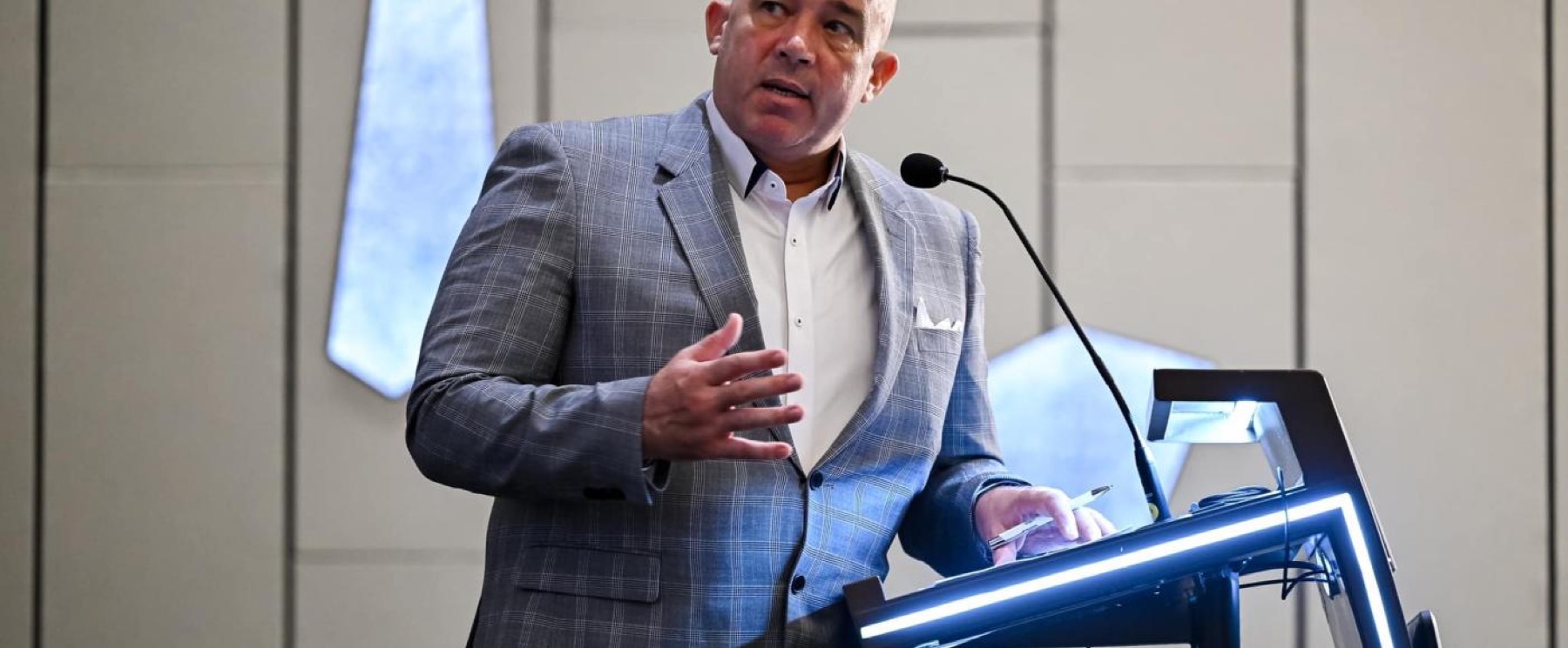 A speaker addressing a room from a lit lectern