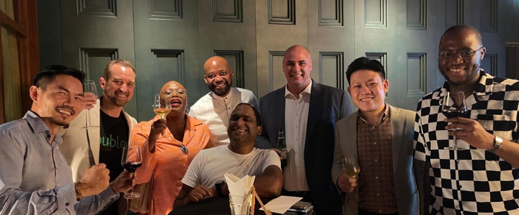Eight members standing together with drinks at a restaurant
