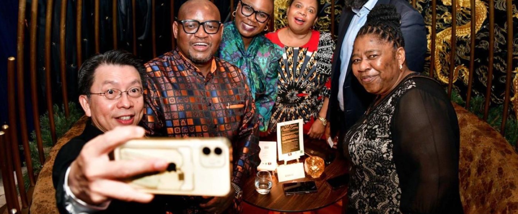 Six members crowding into a photograph together at an evening reception